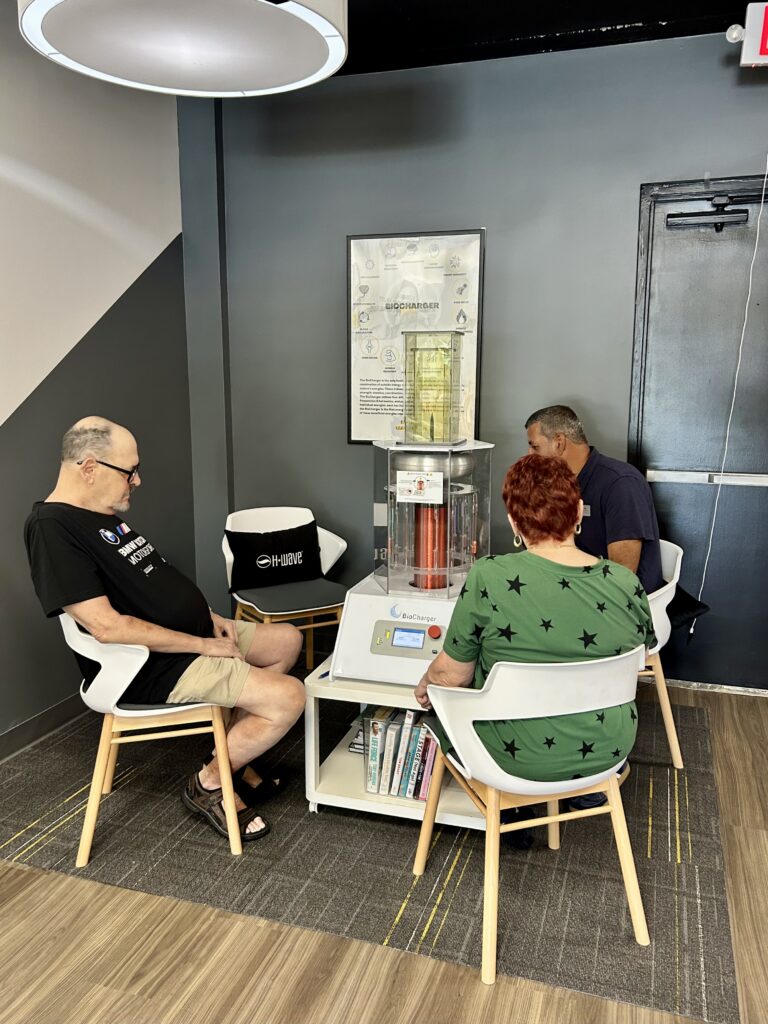 OsteoStrong Juno Beach members Jim, Linda and Lou sitting together around the BioCharger in the studio lounge