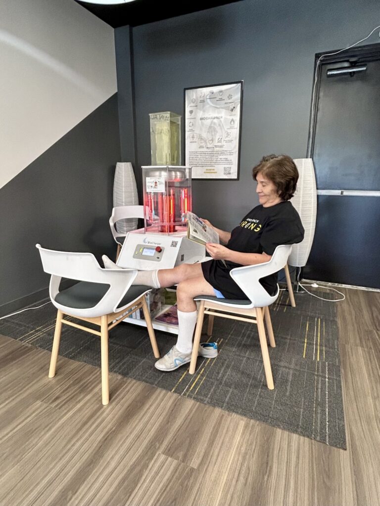 Maria, an OsteoStrong Juno Beach member, relaxing with a magazine beside the BioCharger in our studio
